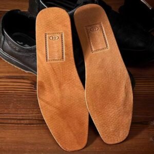 Semelle en cuir souple et raffinée sur un support en bois marron avec une paire de chaussure noire